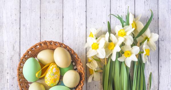 Eggs in a basket and flowers on a padded wooden background