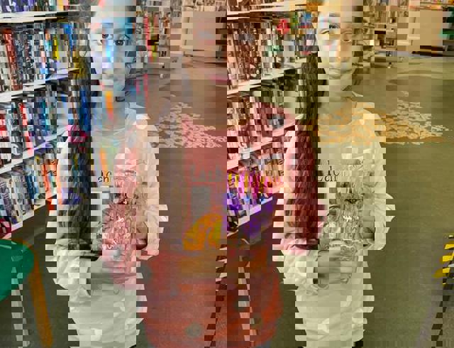 Girl in library holding glass