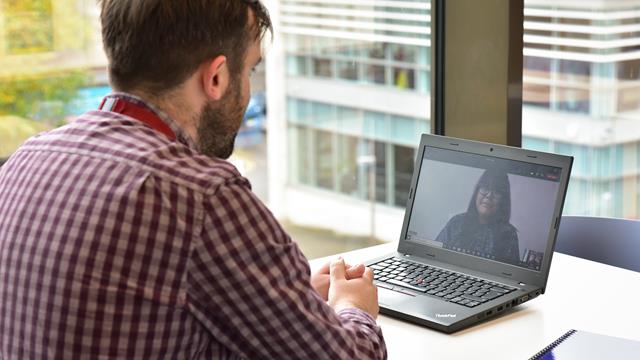 man talking on video call to woman in office
