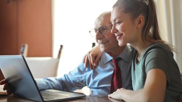 a woman looking at a laptop with an older man