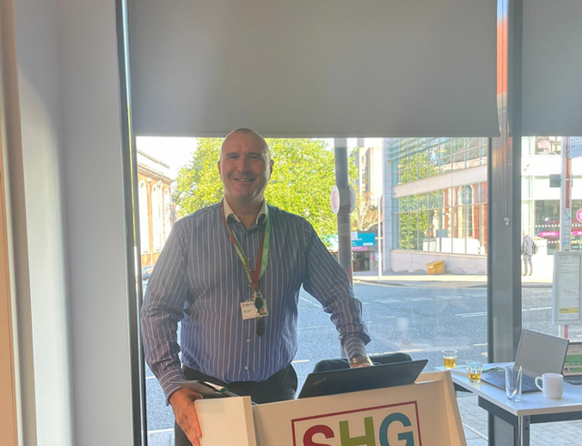Funding Officer stood in front of an SHG lectern