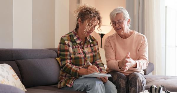 woman helping another older woman inside a home