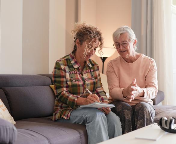 woman helping another older woman inside a home